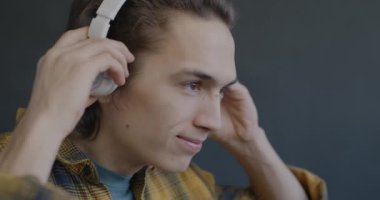 Siyah arka planda kulaklıkla müzik dinleyen kaygısız genç adam. Modern teknoloji ve eğlence konsepti.