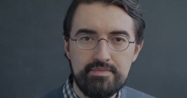 Siyah stüdyo arka planındaki kameraya gülümseyen neşeli Orta Doğulu adamın yavaş çekim portresi. İnsanlar ve olumlu duygu kavramı.