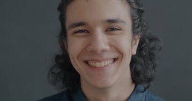 Neşeli İspanyol adamın portresi. Gri arka plandaki kameraya bakarak eğleniyor. Mutlu insanlar ve olumlu duygu kavramı.