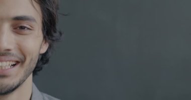 Siyah stüdyo arka planındaki kameraya bakıp gülen neşeli Orta Doğulu bir adamın yakın plan portresi. İnsanlar ve eğlence konsepti.