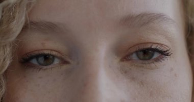 Sakin bir kadın duygularını ifade etmezken kameraya bakan kadın gözlerine yakın çekim. İnsan vücudu ve yüz ifadesi kavramı.