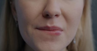 Gri arka planda mutsuz hisseden, dudaklarını ısıran gergin genç bir kadının yakın plan portresi. Negatif duygu ve insan vücudu parçası konsepti.