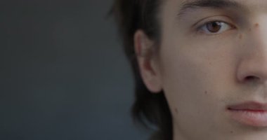 Siyah arka planda sakin bir ifadeyle kameraya bakan yarı insan portresi. İfade ve duygu kavramı.