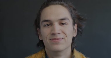 Siyah arka planda kameraya bakıp gülen neşeli genç adamın portresi. Olumlu duygu ve eğlence kavramı.