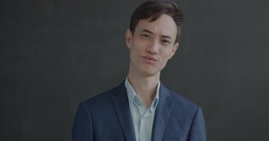 Hayal kırıklığına uğramış takım elbiseli bir gencin ağır çekim portresi. Siyah stüdyo arka planında baş sallayarak el hareketi gösteriyor.