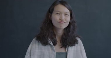 Hayal kırıklığına uğramış Asyalı kadın portresi siyah arka planda el hareketleriyle başını sallıyor. İnsanlar ve olumsuz duygu kavramı.