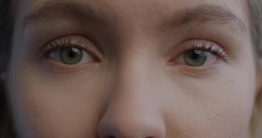 Bayanların gözlerinin yakın plan portresi duygusuzca göz kırpan kameraya bakıyor. İnsan vücudu ve yüz ifadesi kavramı.