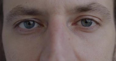 Genç adamların yakın plan portresi duygusuzca yanıp sönen kameraya bakıyor. Yüz ifadesi ve insan vücudu parçası kavramı.