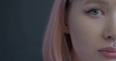 Siyah arka planda duygusuz bir şekilde kameraya bakan çekici genç bir kadının yakın plan portresi. İfade ve insan kavramı.