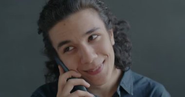 Cep telefonuyla konuşan mutlu İspanyol adamın portresi siyah stüdyo arka planında gülümsüyor. İletişim ve cep telefonu bağlantısı kavramı.