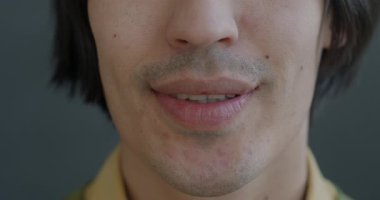 Erkek ağzının yakın çekimi gri arka planda mutluluğu ifade eden gülümseme. Pozitif duygu ve insan vücudu parçası konsepti.