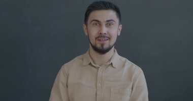 Kameraya bakan heyecanlı melez adamın yavaş çekimde çekilmiş portresi siyah arka planda iyi haberlerin tadını çıkarıyor. İnsanlar ve olumlu duygu kavramı.