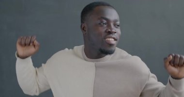 Gri arka planda dans eden, kaygısız Afrikalı Amerikalı adam. Eğlence ve iyi ruh hali konsepti.