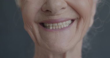 Siyah arka planda gülümseyen neşeli yaşlı kadınların yavaş çekimleri. Olumlu duygular ve yaşlılar konsepti.