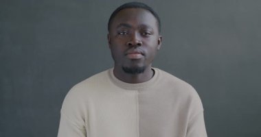 Siyah arka plandaki kameraya bakarak el hareketi yapan mutsuz bir Afrikalı Amerikalı 'nın ağır çekim portresi.