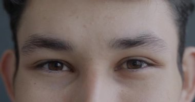 Mutlu Asyalı erkeklerin yakın plan portresi gri arka planda neşe ifade eden kameraya bakıyor. İnsanlar ve olumlu duygu kavramı.