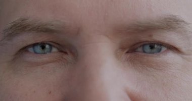 Yavaş çekimde, olgun bir adamın gözlerinin, kameranın yanıp sönen yüzüne bakışının, duygusuz bir portresi. Yüz ifadesi ve insanların konsepti.