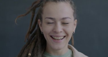 Siyah arka planda kameraya bakıp gülen aşırı neşeli genç bir kadının ağır çekim portresi. İnsanlar ve eğlence konsepti.