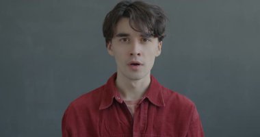 Siyah arka planda kötü sürprizden dolayı kameraya bakan genç adamın yavaş çekim portresi. İnsanlar ve duygu kavramı.