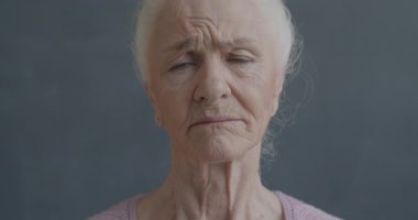 Zavallı yaşlı bir kadının yavaş çekim portresi. Kameraya bakıyor. Üzgün ve yalnız hissediyor..