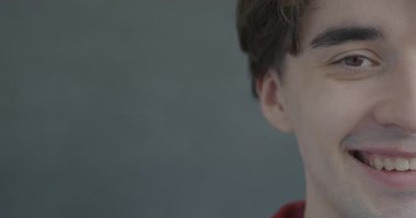 Siyah arka planda kameraya bakıp gülümseyen neşeli yarım yüzlü adamın yavaş çekimleri. İnsanlar ve olumlu duygu kavramı.