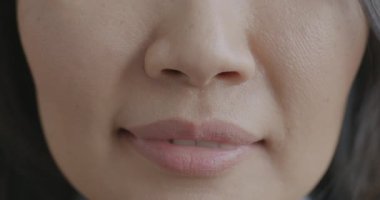 Genç bayanın ağzı gülümserken kadının kendini mutlu ve rahat hissettiği yavaş çekimde. Pozitif duygu ve yüz ifadesi kavramı.