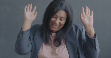 Siyah arka planda kameraya bakarken dans eden kaygısız genç bir kadının yavaş çekim portresi. İnsanlar ve eğlence konsepti.