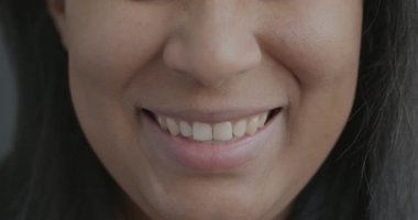 Genç kadın ağzının gülümseyerek mutluluğu ifade eden yavaş çekim portresi. Pozitif duygu ve neşeli insanlar konsepti.
