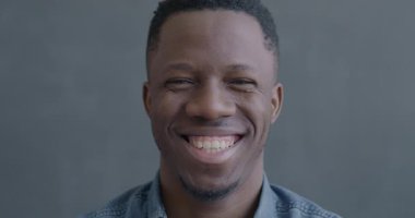 Siyah arka planda kameraya bakıp eğlenen kaygısız Afrikalı Amerikalı adamın yavaş çekim portresi. İnsanlar ve iyi ruh hali kavramı.