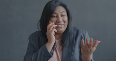 Cep telefonunda gülümseyen mutlu, melez bir kadının portresi. Siyah arka planda sohbetten keyif alıyor. İnsanlar ve iletişim konsepti.