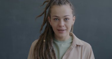 Kameraya bakan mutlu genç kadının yavaş çekim portresi siyah arka planda güzel bir sürprizle heyecanlanıyor. İnsanlar ve duygu kavramı.