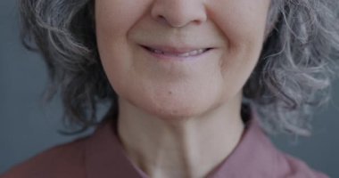 Son sınıf öğrencisi bir kadının gri arka planda gülümseyen yüzünün yakın plan portresi. İnsanlar ve olumlu duygu kavramı.