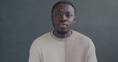 Siyah arka planda gülümseyen mutlu Afrikalı Amerikalı adamın yavaş çekim portresi. İnsanlar ve ifade kavramı.