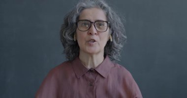 Son sınıf öğrencisinin portresi kulaklıkları takıp, el sallayarak gri arka planda kameraya bakarken çekilmiş..