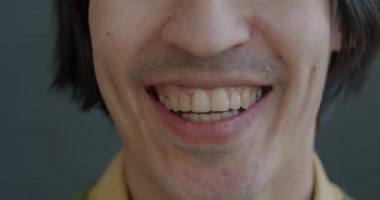 Gri arka planda gülen neşeli genç adamların yavaş çekimleri. Pozitif duygu ve insan yüzü ifadesi kavramı.