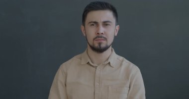 Siyah arka planda şaşkın bir şekilde kameraya bakan melez bir gencin ağır çekimde portresi. İnsanlar ve olumsuz duygu kavramı.