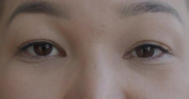 Genç Asyalı kadınların kameraya duygusuz bakışlarının yavaş çekimde çekilmiş portresi. Yüz ifadesi ve insanların konsepti.