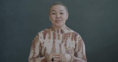 Neşeli Asyalı kadın portresi çevrimiçi video konuşması yapıyor kameraya bakıyor siyah arka planda kulaklık kullanıyor. İletişim ve sanal buluşma kavramı.