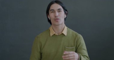 Neşeli Asyalı bir adamın portresi çevrimiçi video görüşmesi yapıyor kameraya kablosuz kulaklıkla bakıyor. İletişim ve insan kavramı.