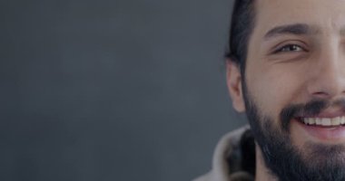 Orta Doğulu neşeli bir adamın gri arka plandaki kameraya gülen yüzünün portresi. Mutlu insan ve pozitif duygu kavramı.