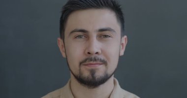 Gri arka planda duygusuz bir şekilde kameraya bakan ciddi bir melez gencin portresi. İnsanlar ve yüz ifadesi kavramı.