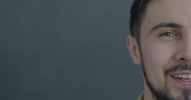Siyah arka planda kameraya bakarak gülen neşeli melez bir adamın yavaş çekim portresi. İnsanlar ve olumlu duygu kavramı.