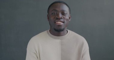 Siyah arka planda gülümseyen Afrikalı Amerikalı 'nın yavaş hareket eden portresi. İnsanlar ve memnuniyet ifadesi kavramı.