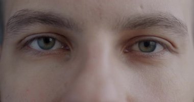 Genç adamların yakın plan portresi duygusuzca yanıp sönen kameraya bakıyor. İnsan vücudu ve yüz ifadesi kavramı.