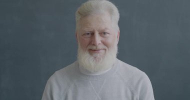 Yaşlı bir adamın el hareketlerini gösteren ve siyah arkaplanda gülümseyen mutlu bir portresi. İnsanlar ve olumlu duygu kavramı.