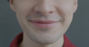 Yavaş çekim portresi, gülümseyen bir adamın gri arka planda gülüşü. İnsanlar ve olumlu duygu kavramı.