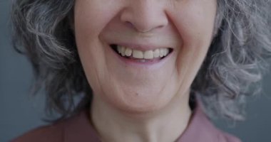Gri arka planda gülen yaşlı kadınların ağızlarının yakın çekimi. Olumlu duygular ve yaşlılar konsepti.