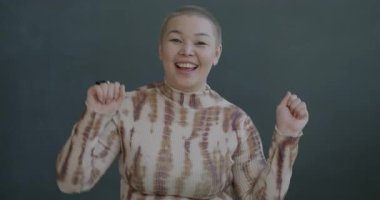 Siyah arka planda kameraya bakarak dans eden Asyalı genç bir kadının yavaş çekim portresi. İnsanlar ve eğlence konsepti.