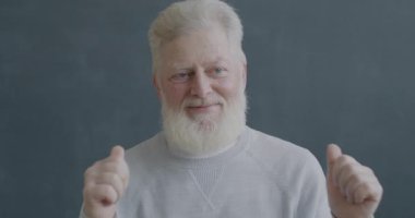 Siyah arka plandaki kameraya bakarak dans eden neşeli yaşlı adamın yavaş çekim portresi. İnsanlar ve eğlence konsepti.