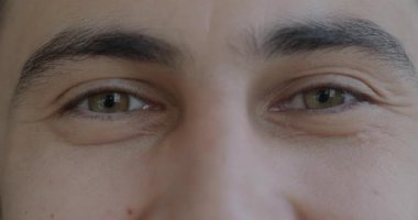 Erkek gözlerinin, mutlulukla gülümseyen ve neşeyle kameraya bakan yavaş çekim portresi. İnsan vücudu ve yüz ifadesi kavramı.